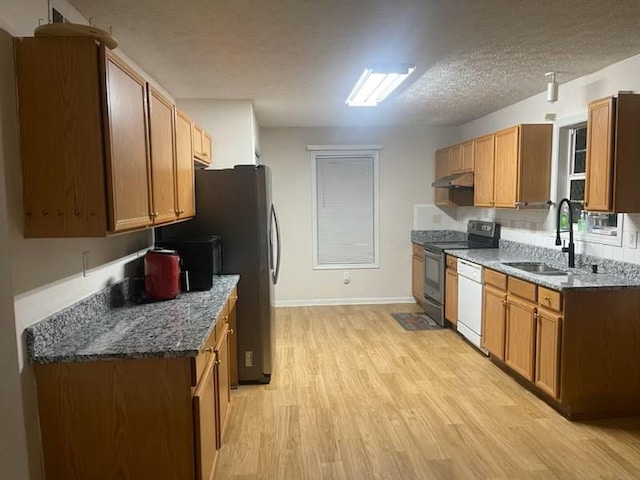 kitchen with light wood-type flooring, dark stone counters, a textured ceiling, sink, and black electric range oven