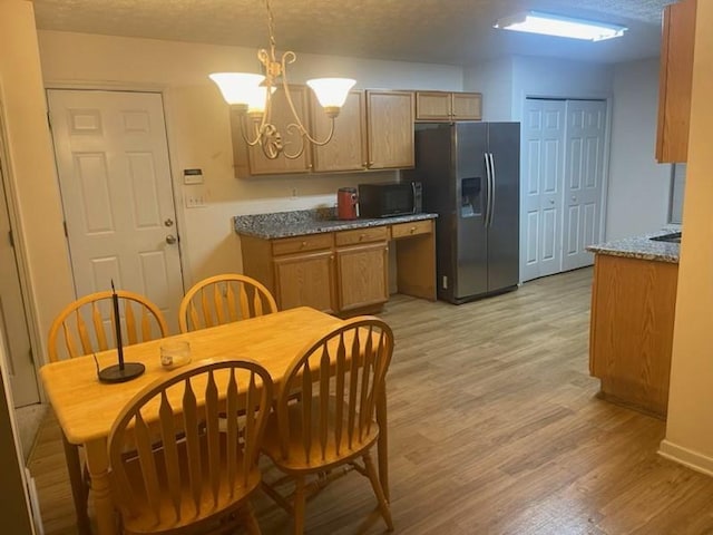 kitchen featuring an inviting chandelier, stainless steel refrigerator with ice dispenser, pendant lighting, a textured ceiling, and light hardwood / wood-style floors