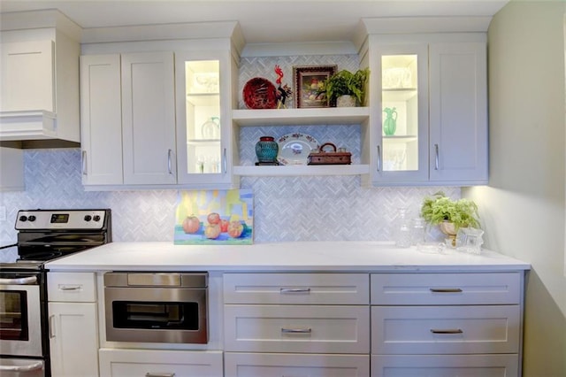 kitchen with decorative backsplash, electric range, and white cabinets