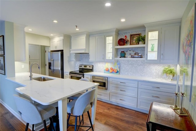 kitchen with a breakfast bar, sink, stainless steel appliances, and white cabinetry