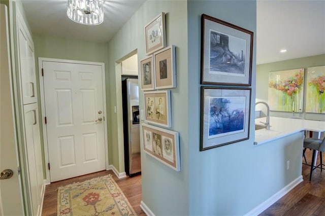 hall with a notable chandelier, sink, and dark hardwood / wood-style floors