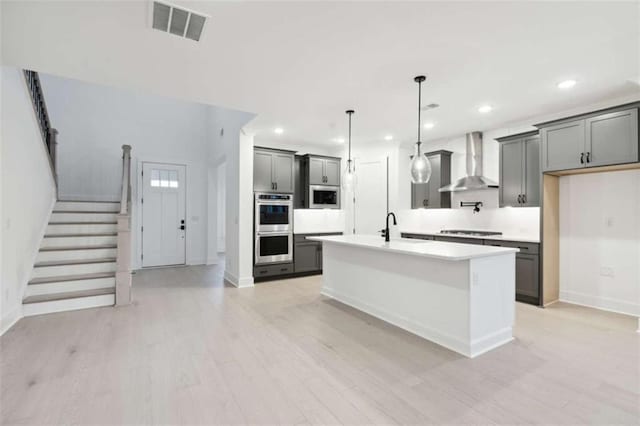 kitchen with baseboards, gray cabinets, visible vents, wall chimney exhaust hood, and double oven