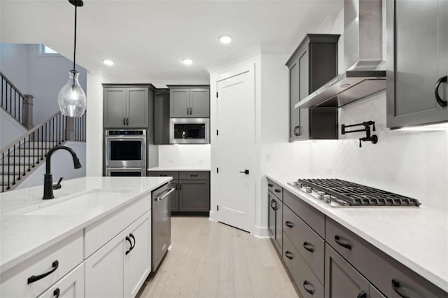 kitchen with appliances with stainless steel finishes, recessed lighting, wall chimney exhaust hood, decorative backsplash, and a sink