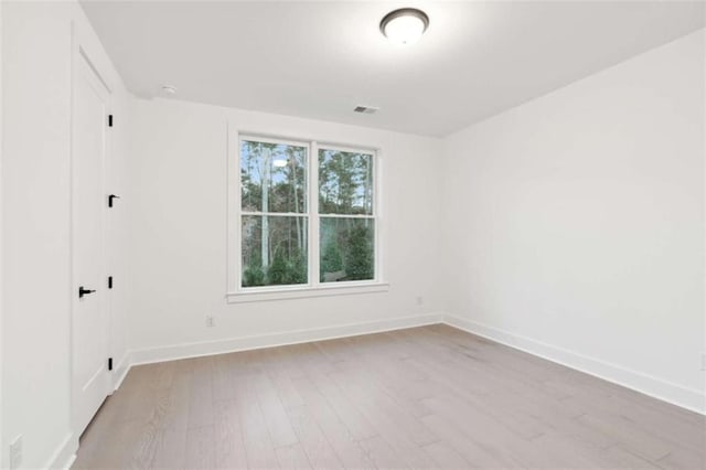 empty room with visible vents, baseboards, and wood finished floors