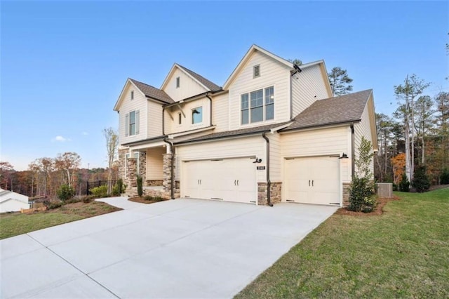view of front of house featuring an attached garage, stone siding, driveway, and a front lawn