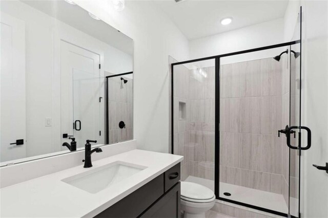 bathroom featuring a shower stall, vanity, and toilet