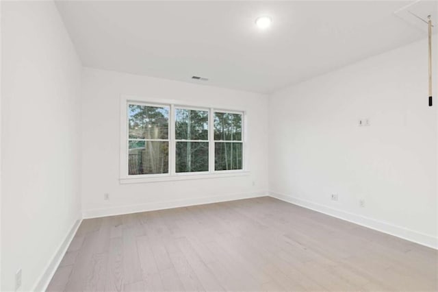 empty room featuring visible vents, baseboards, and wood finished floors