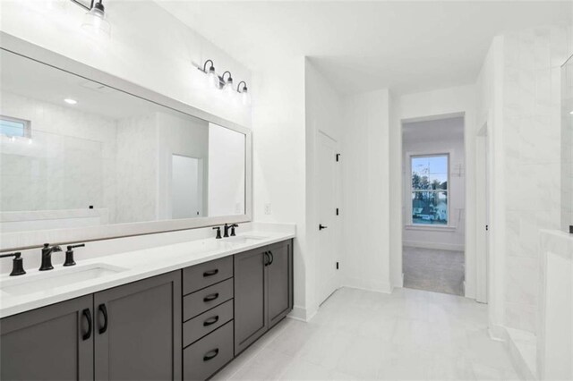 full bath featuring a sink, baseboards, and double vanity