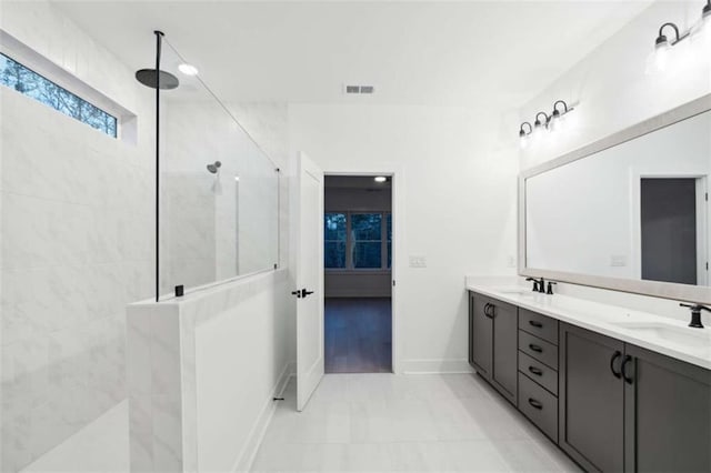 full bath with baseboards, double vanity, walk in shower, visible vents, and a sink