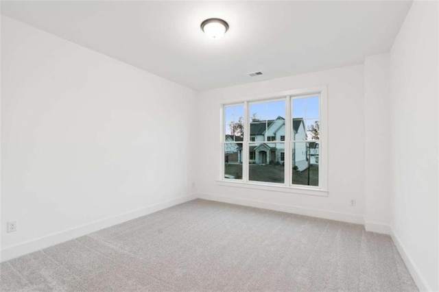 spare room with light carpet, visible vents, and baseboards