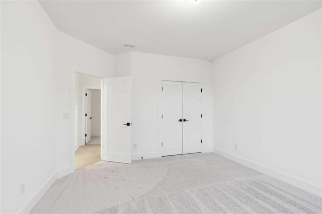 unfurnished bedroom featuring a closet, baseboards, and light carpet