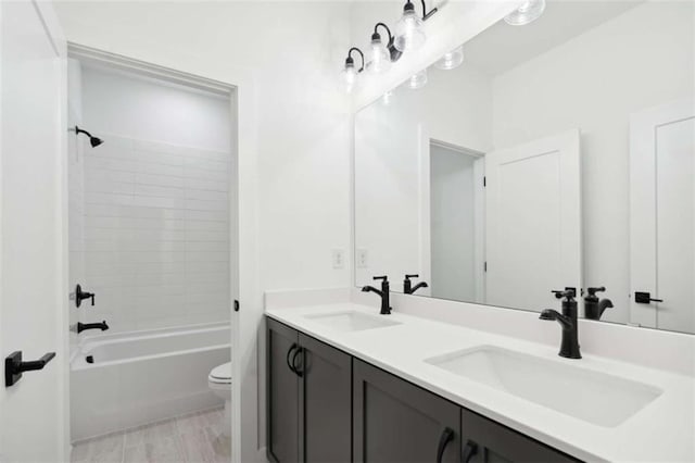 bathroom featuring double vanity, bathtub / shower combination, a sink, and toilet