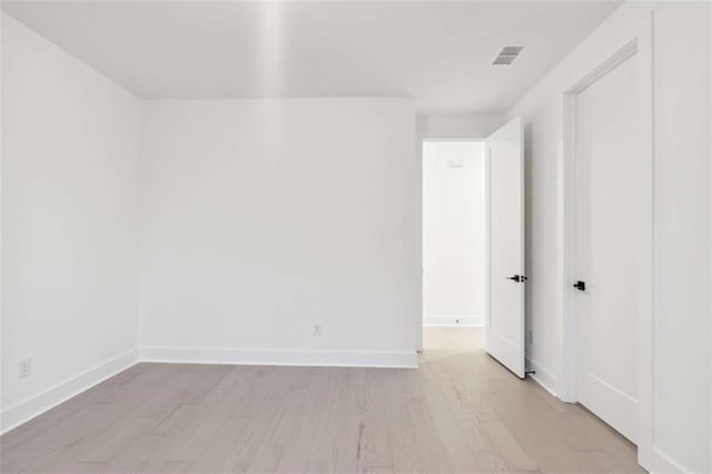 unfurnished room with visible vents, light wood-type flooring, and baseboards