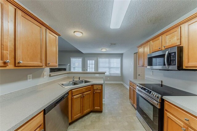 51 Legend Creek Way, Douglasville, GA 30134 - kitchen with a textured ceiling, a sink, light countertops, a peninsula, and stainless steel appliances