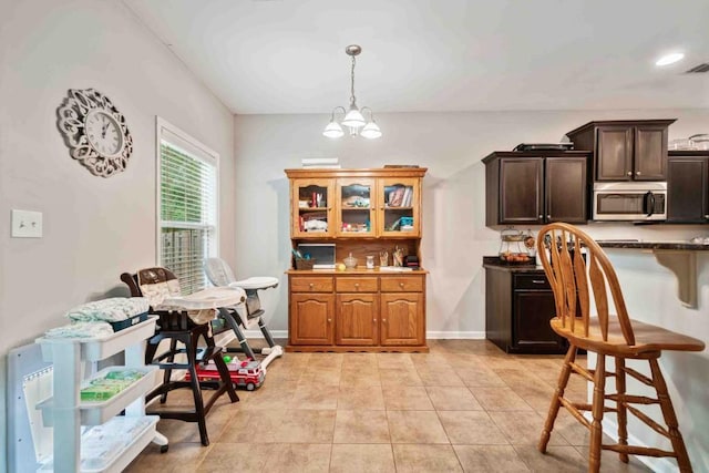 14 Oak Leaf Way, Hamilton, GA 31811 - kitchen featuring stainless steel microwave, a chandelier, pendant lighting, light tile patterned floors, and a breakfast bar