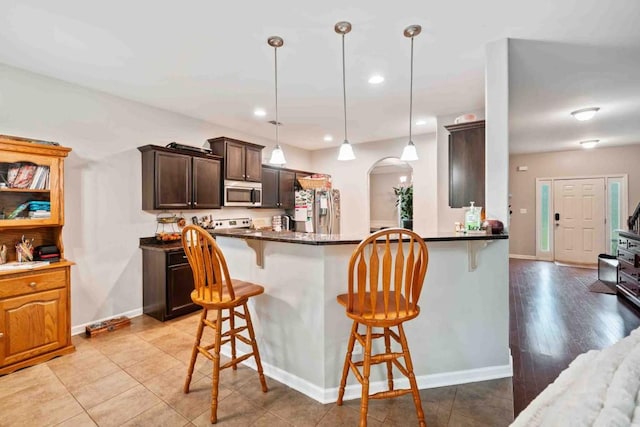 14 Oak Leaf Way, Hamilton, GA 31811 - kitchen with appliances with stainless steel finishes, arched walkways, a breakfast bar, dark brown cabinetry, and dark countertops