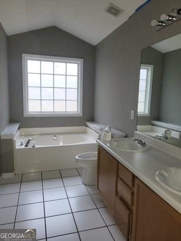 bathroom featuring a garden tub, lofted ceiling, visible vents, a sink, and tile patterned flooring