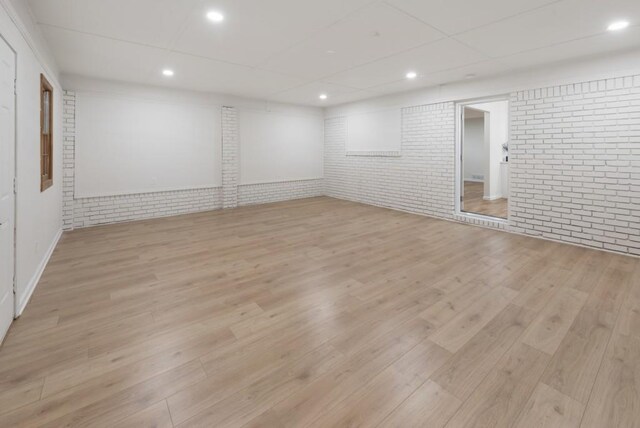 spare room featuring light wood-type flooring and brick wall