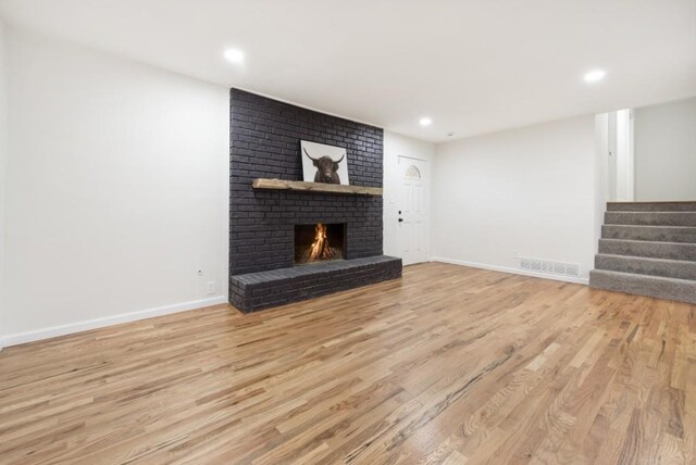 unfurnished living room featuring a brick fireplace and light hardwood / wood-style flooring