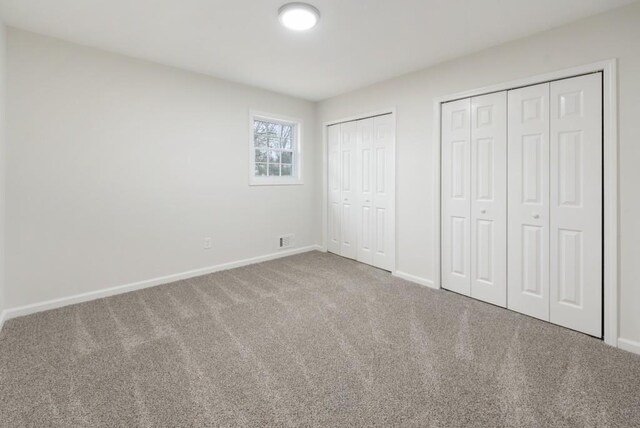 unfurnished bedroom with carpet floors and multiple closets