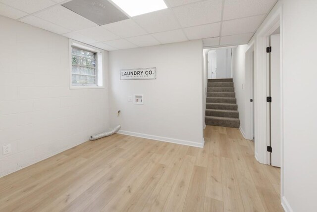 basement with a paneled ceiling and light hardwood / wood-style flooring