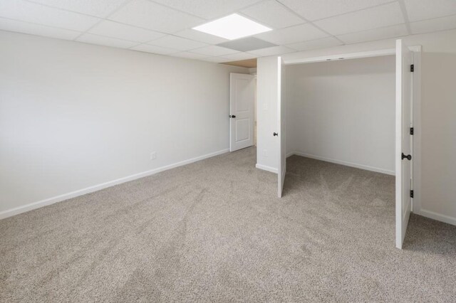 basement with a drop ceiling and light colored carpet