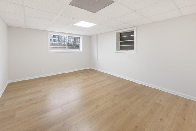 basement featuring a drop ceiling and light hardwood / wood-style flooring