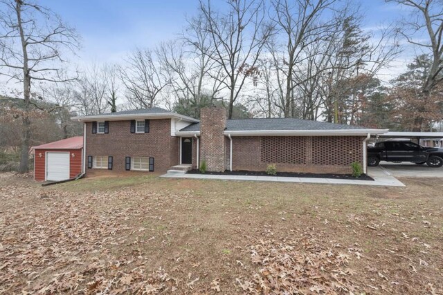 tri-level home featuring a carport, a garage, and an outdoor structure