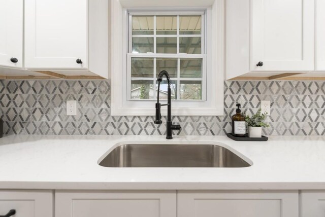 kitchen featuring decorative backsplash, sink, and white cabinets