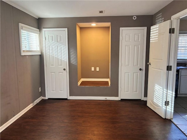 unfurnished bedroom featuring dark wood-style floors, visible vents, and baseboards