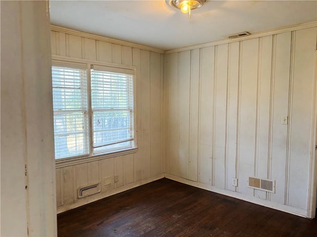 empty room featuring visible vents and dark wood-type flooring