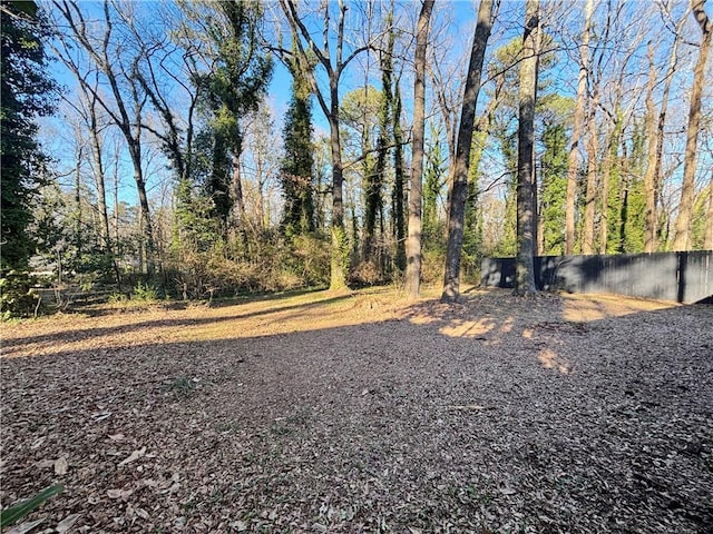 view of yard featuring a forest view and fence