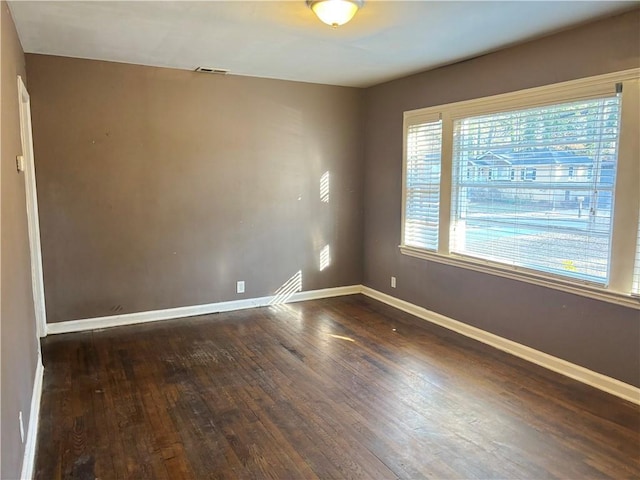 spare room featuring baseboards, visible vents, and wood finished floors