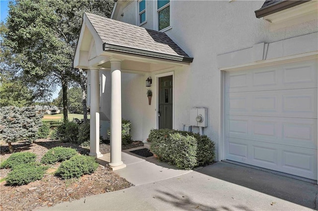 doorway to property featuring a garage, roof with shingles, and stucco siding
