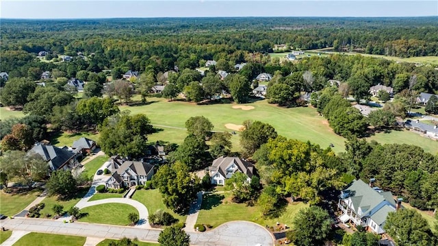 aerial view of property and surrounding area featuring a forest, nearby suburban area, and a local golf course