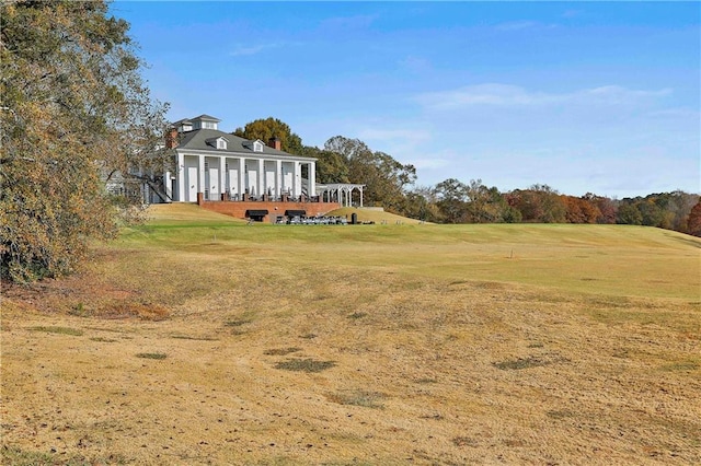 back of house with a yard, a chimney, and golf course view