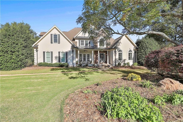 traditional home featuring a front yard, stucco siding, french doors, and a ceiling fan