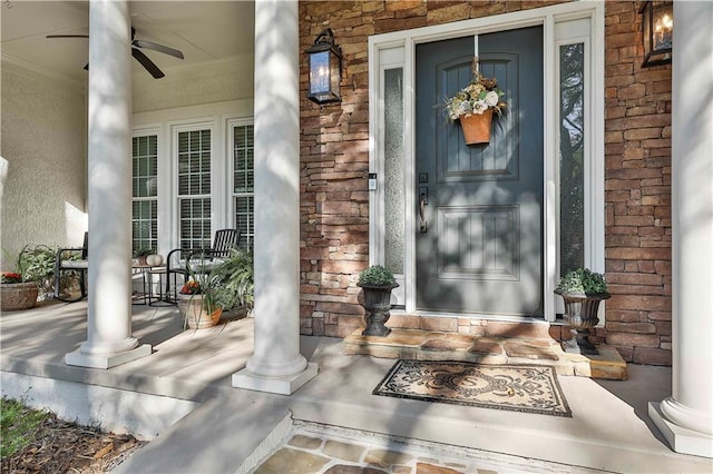 view of exterior entry with a porch, stone siding, and a ceiling fan