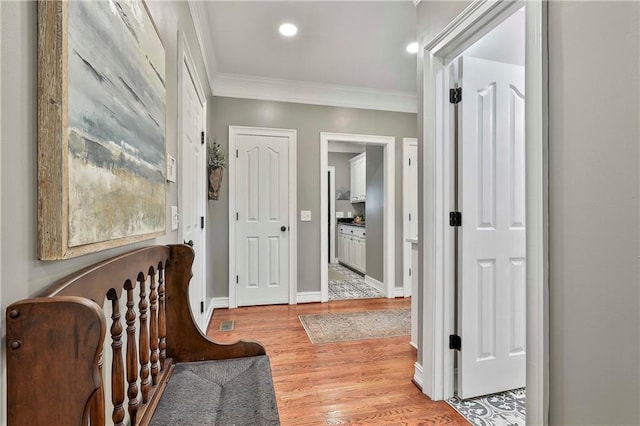 corridor with ornamental molding, light wood finished floors, recessed lighting, and baseboards