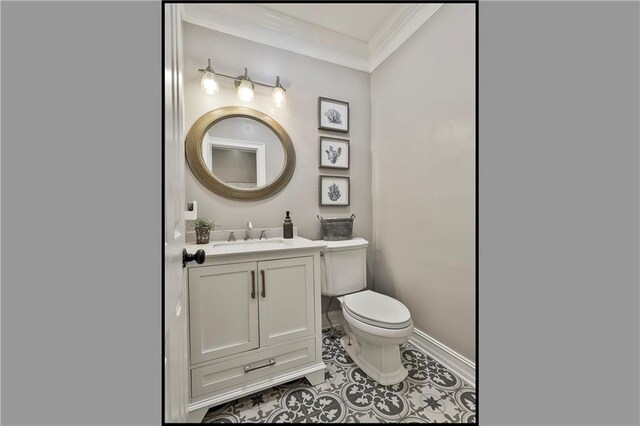 half bath with crown molding, toilet, vanity, tile patterned flooring, and baseboards