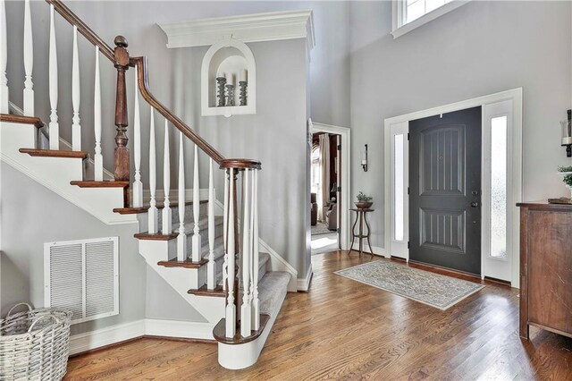 entrance foyer with wood finished floors, stairway, baseboards, and a high ceiling