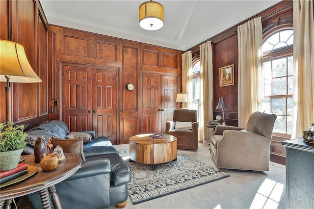 living area with wooden walls and light carpet