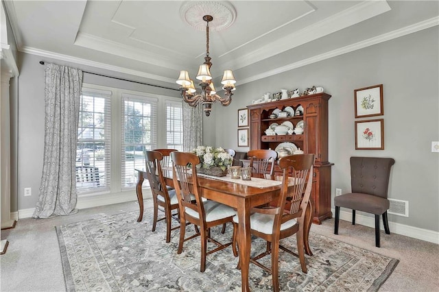 dining room featuring a raised ceiling, a chandelier, light colored carpet, ornamental molding, and baseboards