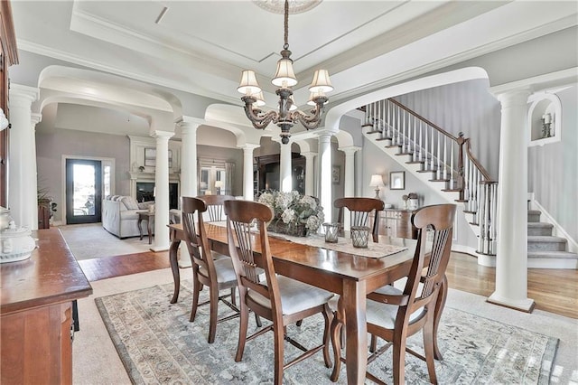 dining space with stairs, crown molding, a raised ceiling, light wood-style floors, and baseboards