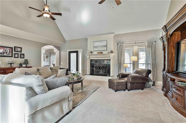living room with a ceiling fan, carpet flooring, arched walkways, high vaulted ceiling, and a fireplace