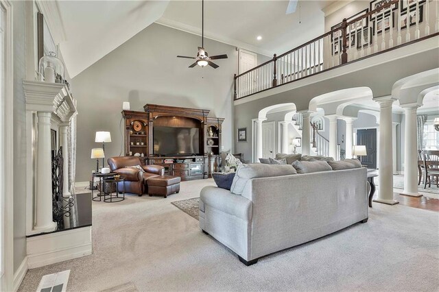 living area featuring ornate columns, a ceiling fan, high vaulted ceiling, carpet, and crown molding