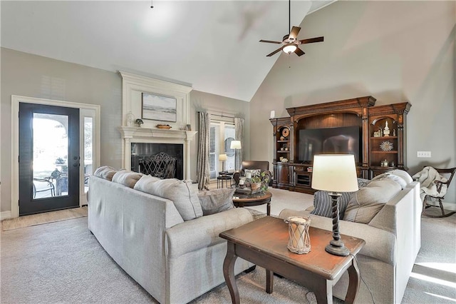 living area featuring ceiling fan, light colored carpet, plenty of natural light, high vaulted ceiling, and a fireplace