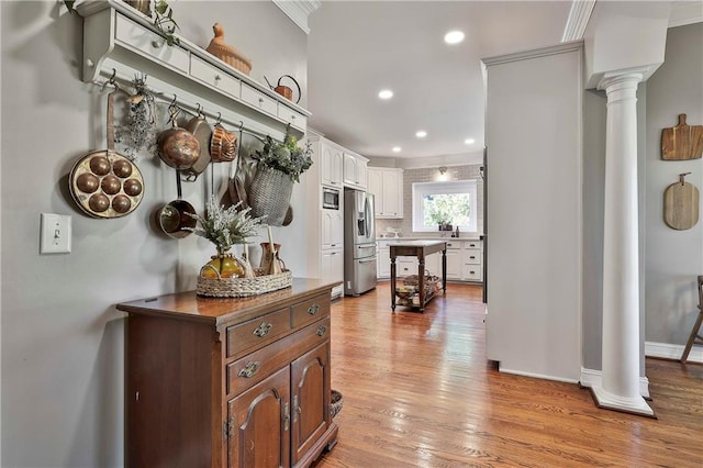 corridor featuring decorative columns, light wood-style floors, recessed lighting, baseboards, and crown molding