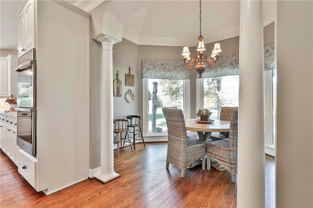 dining room featuring a chandelier, ornamental molding, ornate columns, wood finished floors, and baseboards