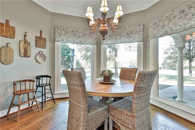 dining room featuring healthy amount of natural light, wood-type flooring, and a chandelier